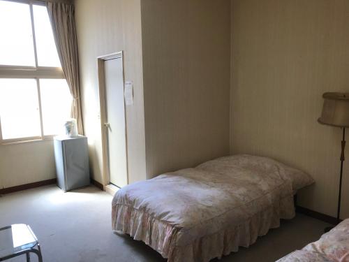 um pequeno quarto com uma cama e uma janela em Yamatoya em Nozawa Onsen