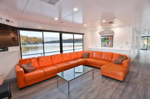a living room with an orange couch and a glass table at All Seasons Houseboats in Mildura