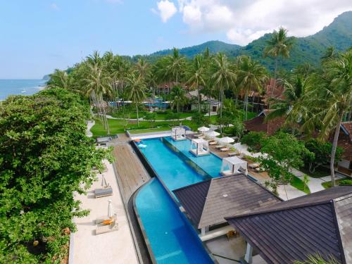an aerial view of a resort pool with palm trees and the ocean at Mangsit Suites by Holiday Resort Lombok in Mangsit