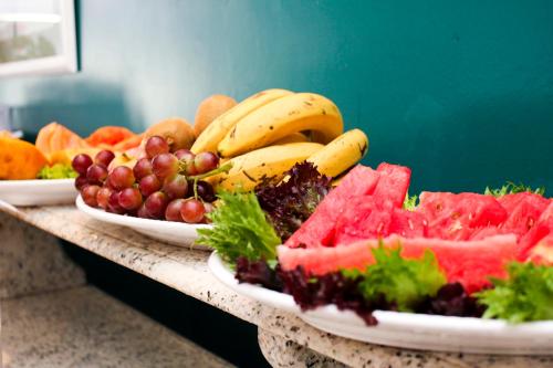 two plates of fruits and vegetables on a table at Vitória Hotel Residence NewPort in Campinas