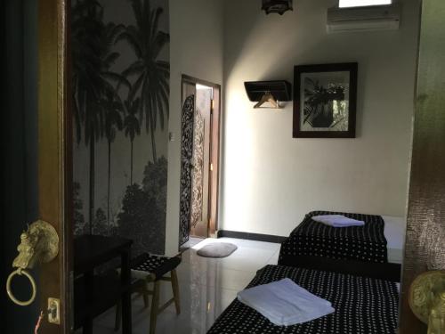 a room with two beds and a table and a door at Gili Nyepi in Gili Trawangan