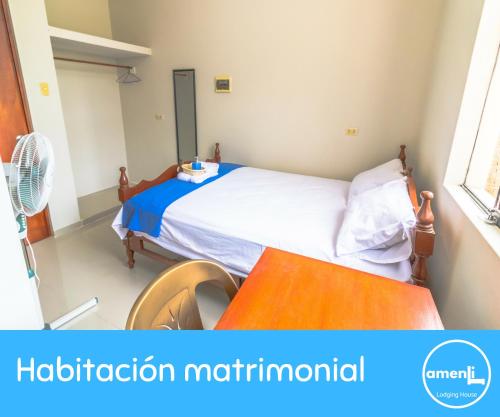 - une petite chambre avec un lit et une table dans l'établissement Amenli Lodging House, à Piura