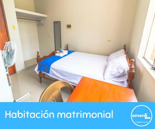 a small bedroom with a bed and a table at Amenli Lodging House in Piura
