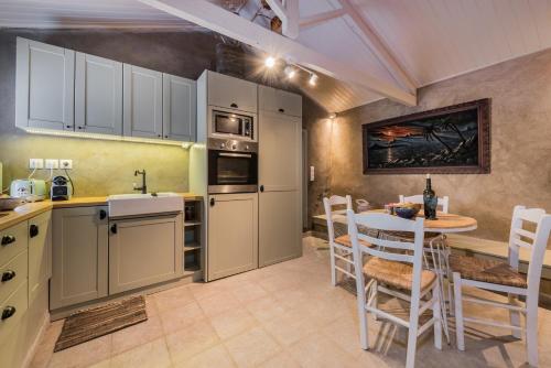 a kitchen with white cabinets and a table with chairs at Ag Thekla Est 1924 in Skinária