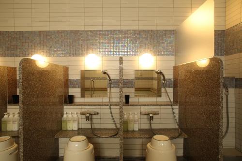 a bathroom with four urinals and sinks and lights at Green Rich Hotel & Capsule Naha - Artificial hot spring Futamata Yunohana in Naha