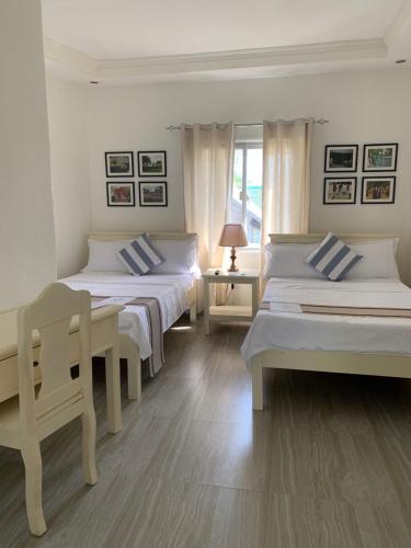 a room with three beds and a table and a window at Isaguirre's Pension House in Baler