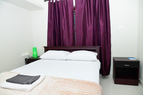 a bedroom with a large bed with purple curtains at Athrakkattu Enclave in Trivandrum