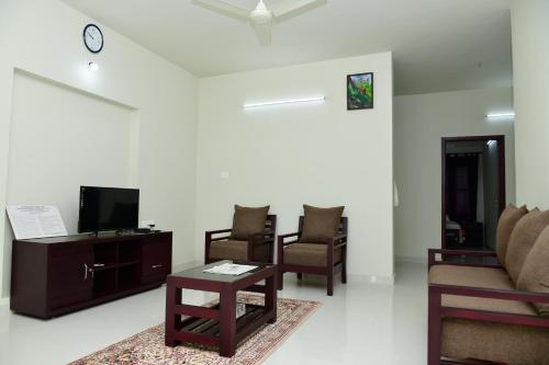 a living room with a couch and chairs and a tv at Athrakkattu Enclave in Trivandrum