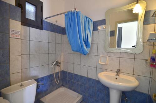 a bathroom with a sink and a toilet and a mirror at Hotel Olympiada in Vráchos