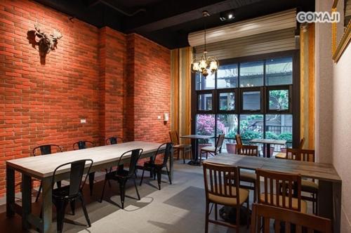 a dining room with tables and chairs and a brick wall at 108 House Inn in Tainan