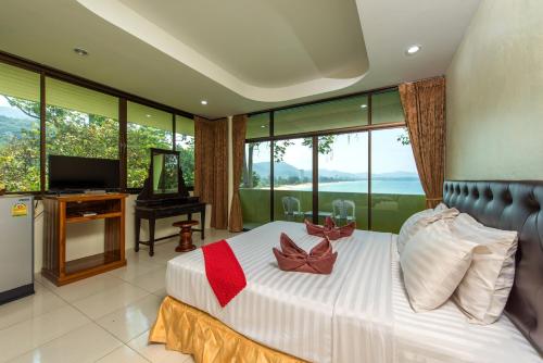 a bedroom with a large bed with a television and windows at Baan Karon Hill Phuket Resort in Karon Beach