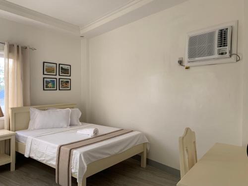 a white bedroom with a bed and a air conditioner at Isaguirre's Pension House in Baler
