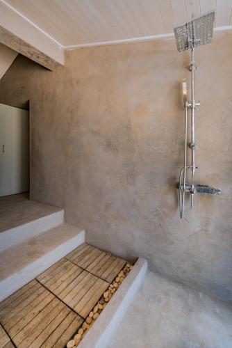 a shower in a room with a stone wall at Ag Thekla Est 1924 in Skinária