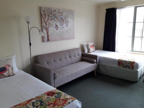 a living room with a couch and a bed at Colonial Lodge Motel in Taupo