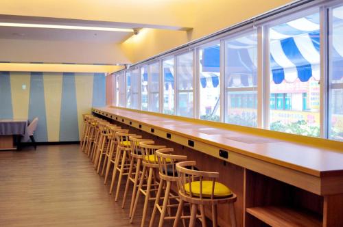 a long bar with yellow chairs and a row of windows at Fish Hotel Kaohsiung in Kaohsiung