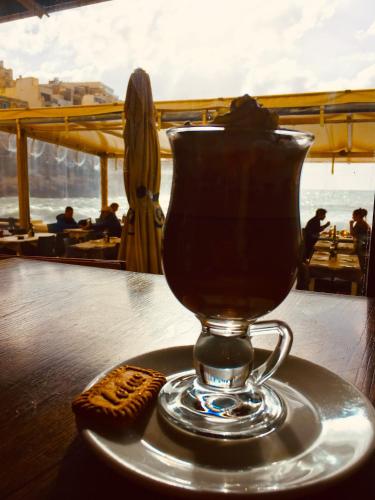 a cup of tea sitting on a table with a cookie at Moby Dick Xlendi Holiday Apartments in Xlendi