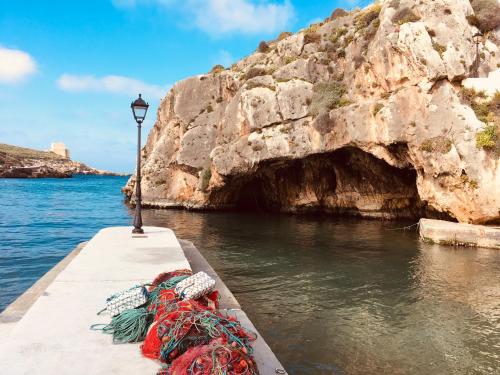 a boat in the water next to a cave at Moby Dick Xlendi Holiday Apartments in Xlendi