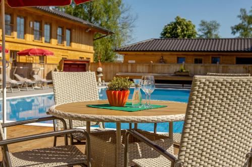 a table with a glass of wine and two chairs at Ruperti - Gästehaus in Ainring