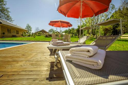a group of lounge chairs with umbrellas and a pool at Ruperti - Gästehaus in Ainring