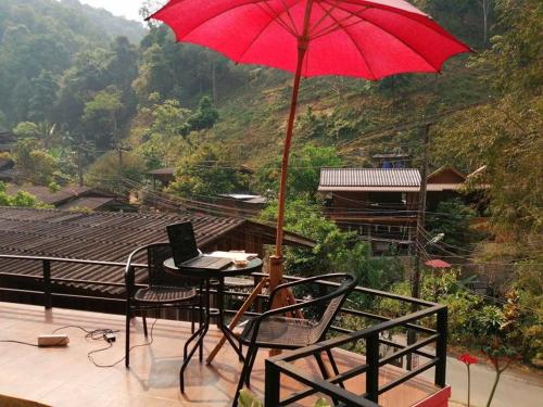 a red umbrella sitting on a balcony with a laptop at Lungphut Homestay in Chiang Mai