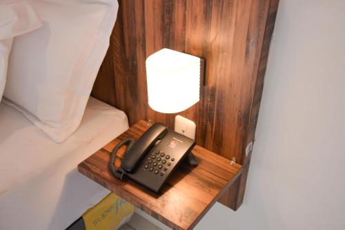 a telephone on a wooden table next to a bed at RedDoorz Plus near UNIMED Medan in Medan