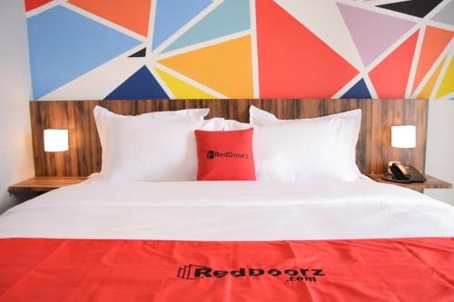 a white bed with red pillows and a colorful wall at RedDoorz Plus near UNIMED Medan in Medan