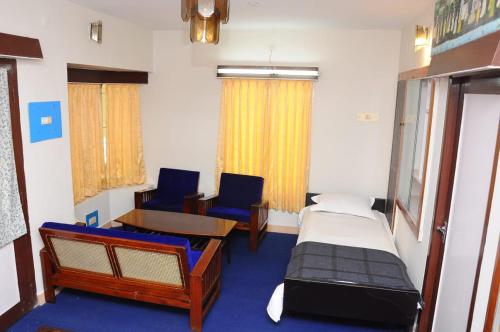 a room with two beds and a table and chairs at Green Woods Homestay in Kodaikānāl