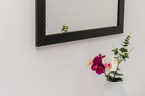 a mirror and a vase with flowers on a wall at Apartments Lorena Mljet in Pomena
