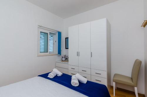 a white bedroom with a bed and a chair at Apartments Lorena Mljet in Pomena