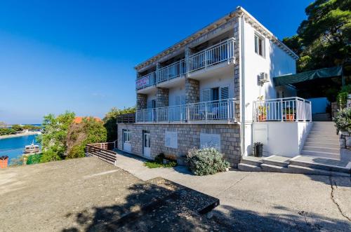 ein weißes Haus mit einem Balkon und einem Fluss in der Unterkunft Apartments Lorena Mljet in Pomena