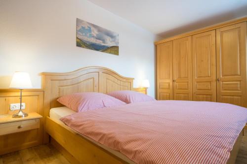 um quarto com uma cama grande e lençóis cor-de-rosa em Ferienwohnungen Alpentraum - Mäusle em Oberstdorf