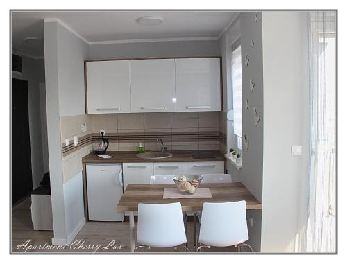 een keuken met witte kasten en een tafel en stoelen bij Apartment Cherry Lux in Zrenjanin