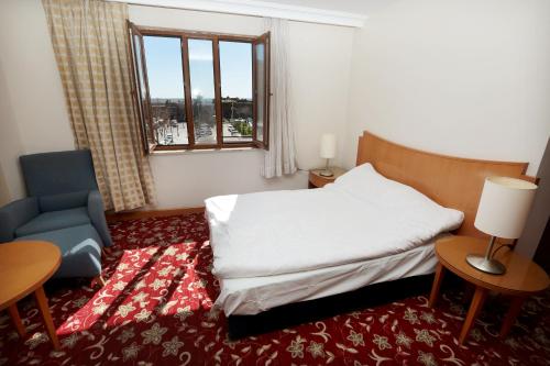 ディヤルバクルにあるDiyarbakır otelのベッドと椅子と窓のある寝室