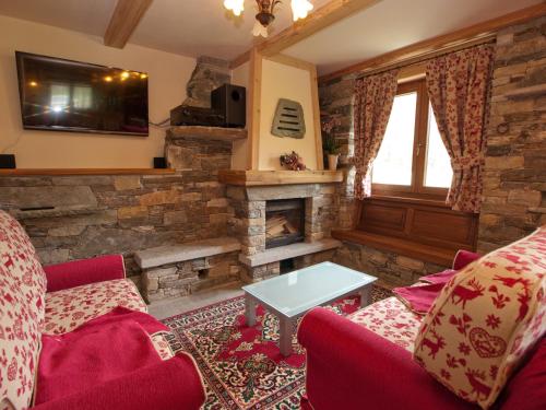 a living room with red furniture and a stone fireplace at Villa Americana Chambres d'Hotes in Champoluc