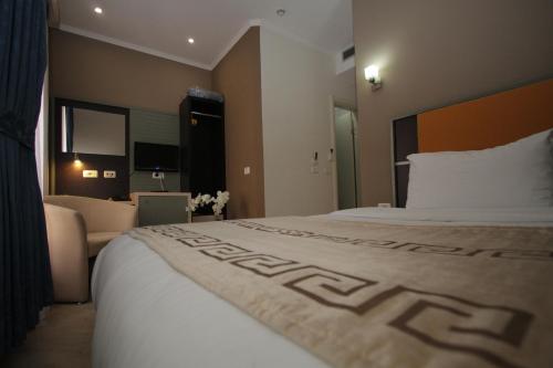 a hotel room with a large bed and a couch at Capital Tirana Hotel Bruçi in Tirana