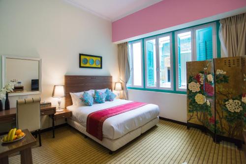 a hotel room with a bed and a desk and windows at Aava Malacca Hotel in Malacca