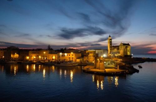 a city at night with lights on the water at B&B MONTEBELLO in Trani