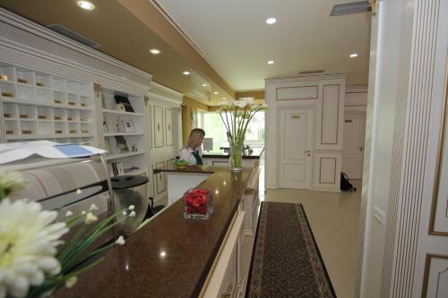 a kitchen with white cabinets and a woman in the background at Capital Tirana Hotel Bruçi in Tirana
