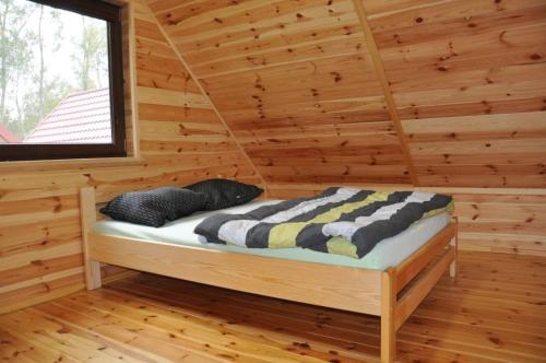 Habitación con cama en una cabaña de madera en Słoneczny Zakątek, en Sztutowo