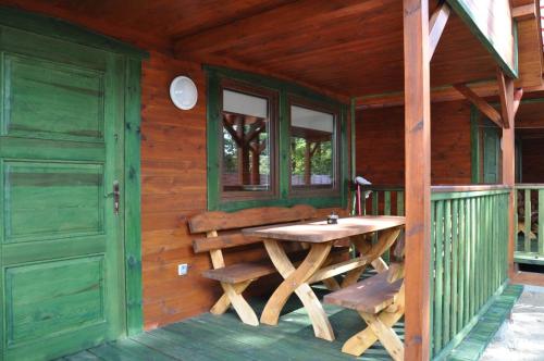 un porche de una cabaña de madera con una mesa de madera en Słoneczny Zakątek en Sztutowo