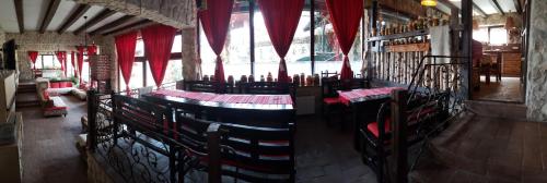 a restaurant with red curtains and tables and chairs at Pensiunea Casa Dacilor in Podeni