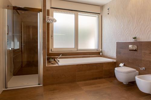 a bathroom with a tub and a toilet and a window at Aurum Suites in Pescara