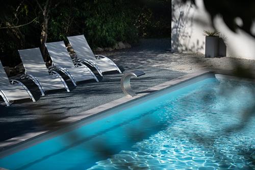 a swimming pool with chairs next to a swimming pool at Mise en Scène in Aumelas