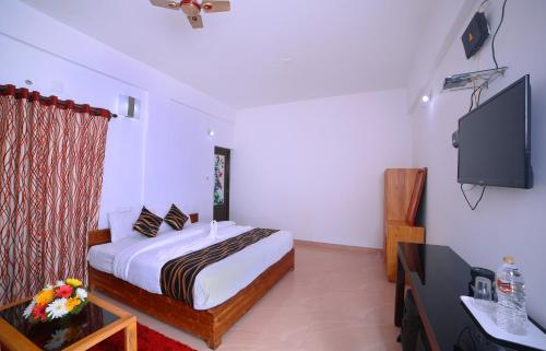 Pine Tree Munnar في مونار: غرفة نوم بسرير وتلفزيون بشاشة مسطحة