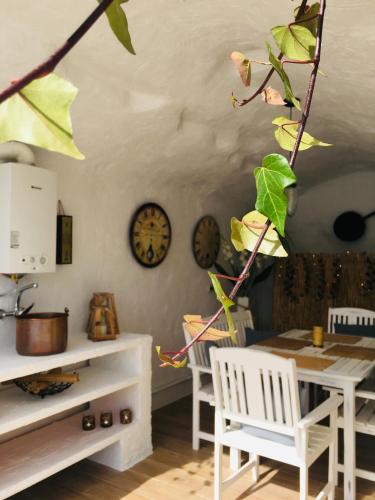 a dining room with a table and chairs and a clock at Cuevas Helena in Benamaurel
