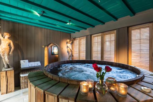 - une grande baignoire dans une chambre avec une table et des fleurs dans l'établissement Exclusive Suites The Secret Garden, à Bruges