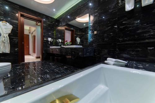 a bathroom with a tub, sink and mirror at Warwick Al Khobar in Al Khobar