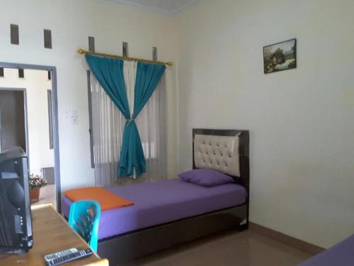 Penginapan Syariah في Parit: غرفة نوم صغيرة بسرير وستارة زرقاء