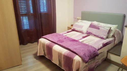 バレンシア・デ・アヌーにあるCasa Ponetのベッドルーム(紫の毛布付きのベッド1台付)