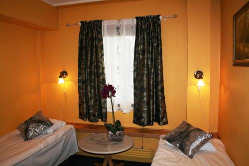 a room with two beds and a window with a table at Barents Hotell in Kirkenes